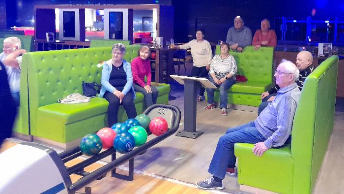 9 Teilnehmer am Bowlingabend, die den Verlauf des Wettkampfes verfolgen.