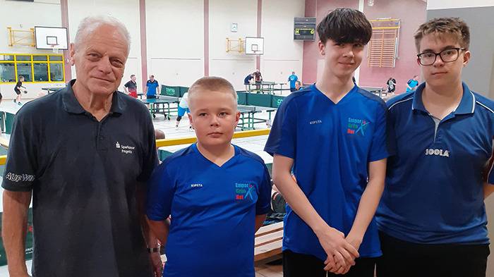 Tischtennisvertretung 3 Jugendliche und 1 Erwachsener in der Sporthalle, im Hintergrund Tischtennisplatten und Spieler
