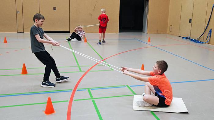 2 Personen ziehen 2 weitere über den Hallenboden