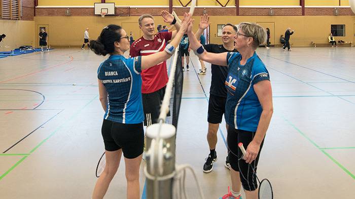 vier Spieler:innen klatschen auf dem Feld am Spielende ab