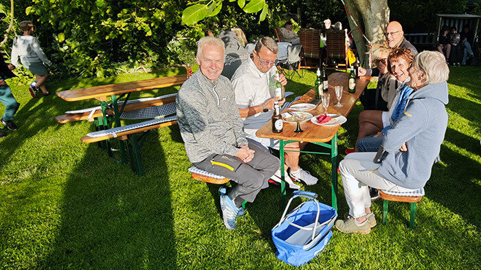 Personen auf Bänken unterm Baum